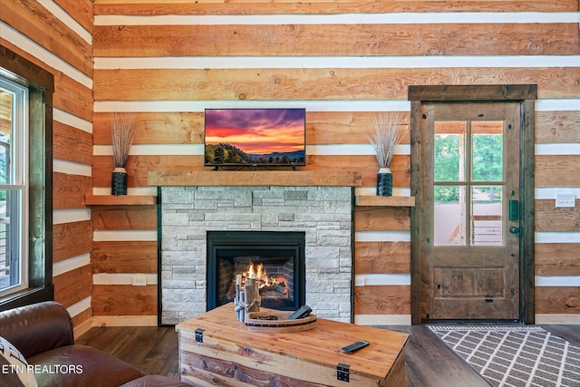 living room featuring a fireplace, dark hardwood / wood-style flooring, and wood walls