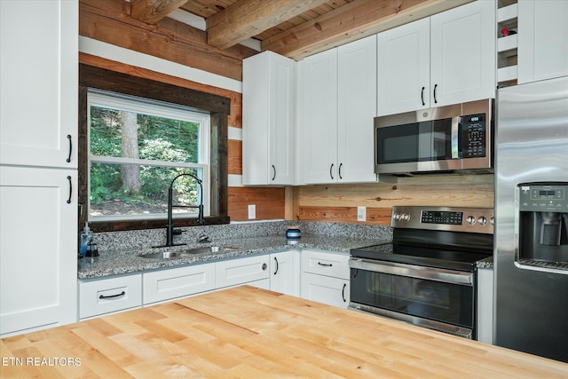 kitchen with white cabinetry, light stone countertops, appliances with stainless steel finishes, and sink