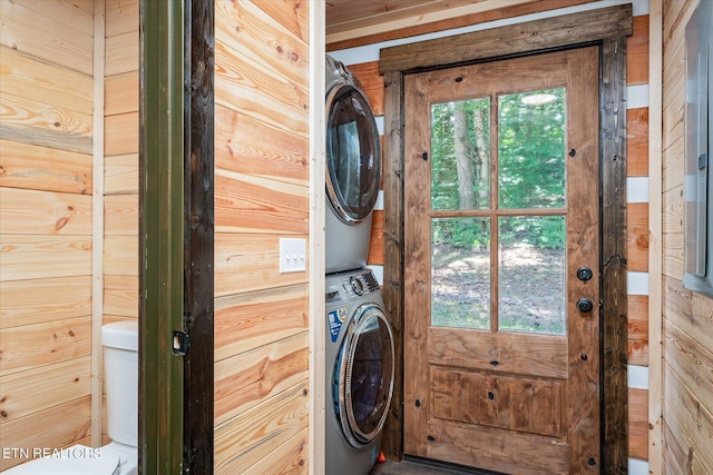 clothes washing area with stacked washer / dryer and wood walls