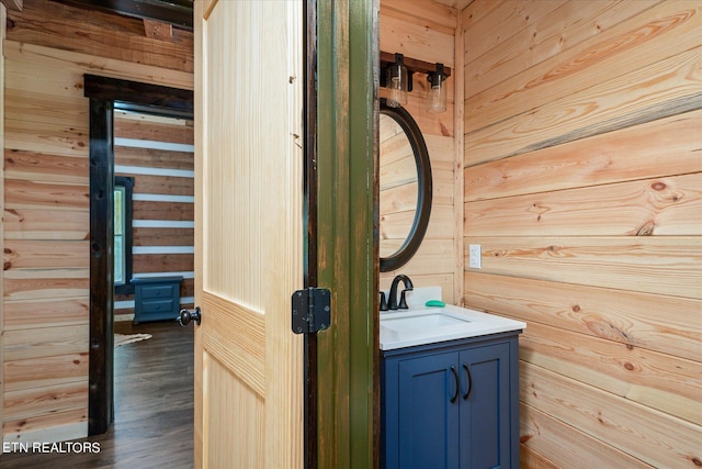 bathroom with vanity, wooden walls, and hardwood / wood-style floors