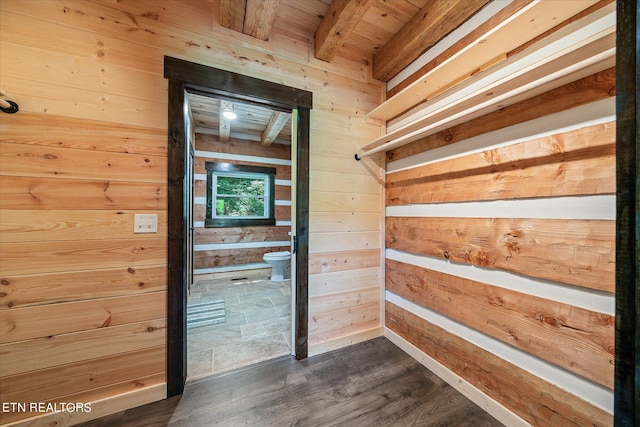 interior space featuring beamed ceiling, dark hardwood / wood-style flooring, and wooden walls