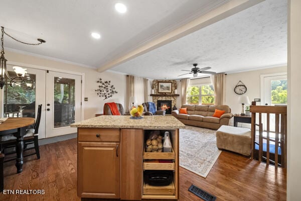 kitchen with a large fireplace, a center island, ceiling fan with notable chandelier, and dark hardwood / wood-style floors