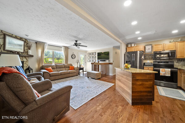 living room featuring ceiling fan, a textured ceiling, crown molding, and hardwood / wood-style flooring