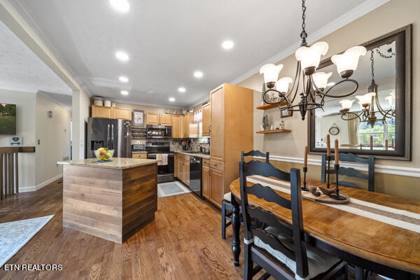 kitchen with black appliances, hardwood / wood-style flooring, pendant lighting, an inviting chandelier, and backsplash