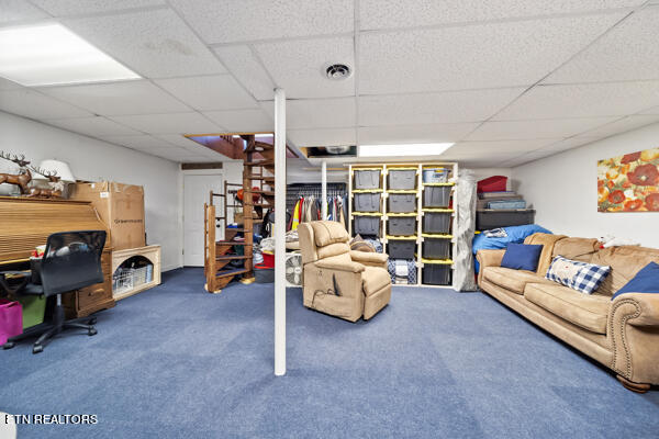 living room featuring a drop ceiling and carpet flooring