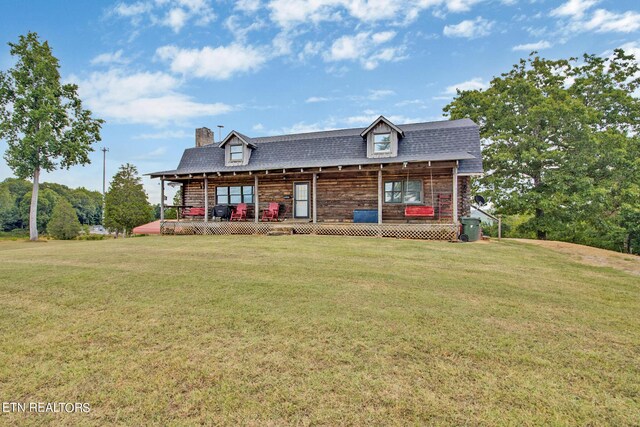 view of front of home with covered porch, a shingled roof, a chimney, and a front lawn