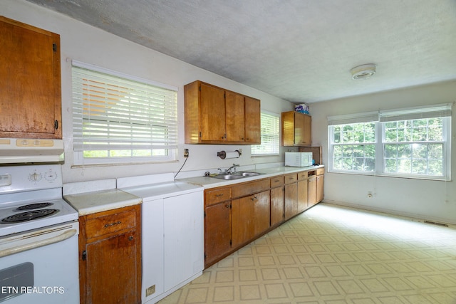 kitchen with white appliances, light tile patterned floors, washer / clothes dryer, range hood, and sink