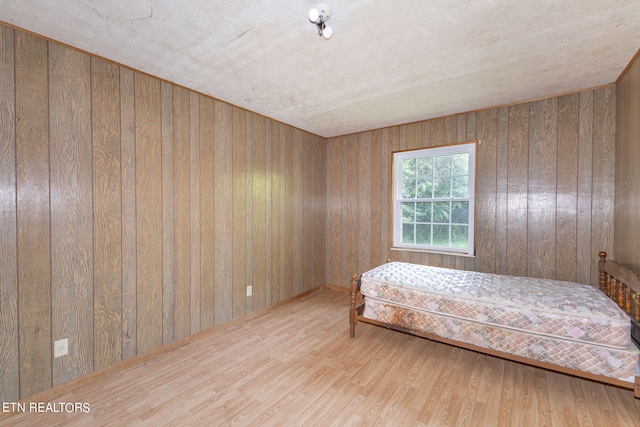 bedroom with light wood-type flooring and wooden walls