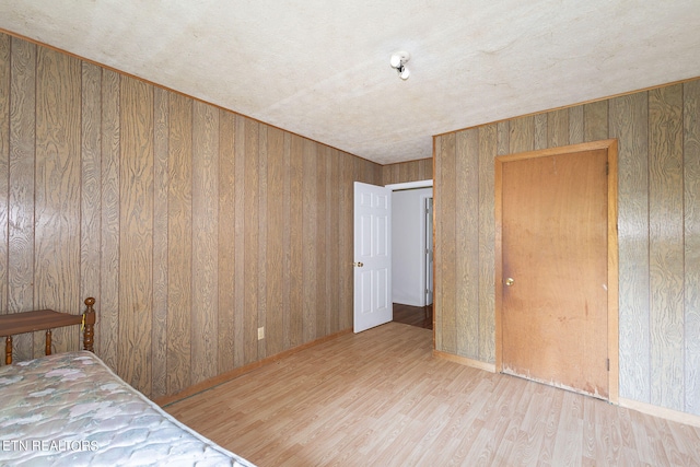 unfurnished bedroom with hardwood / wood-style flooring and wooden walls