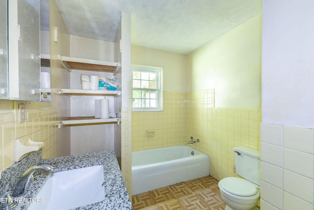 full bathroom featuring vanity, toilet, a textured ceiling, and tile walls