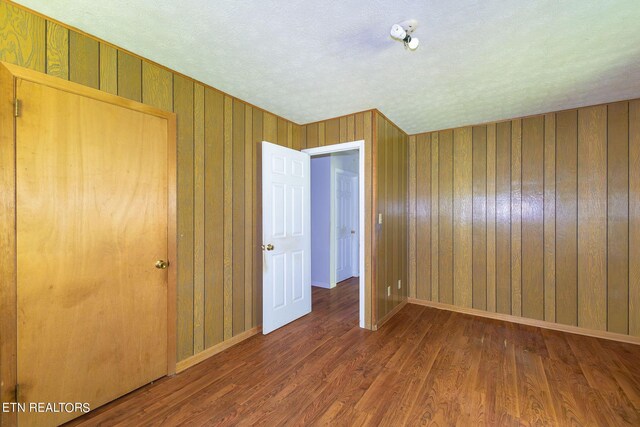 unfurnished bedroom with a textured ceiling, dark hardwood / wood-style flooring, and a closet