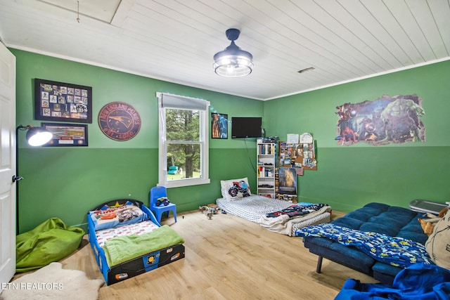 bedroom with wood ceiling, wood finished floors, attic access, and crown molding