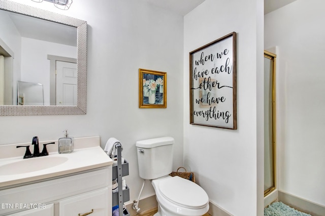 bathroom with toilet, a shower with shower door, and vanity