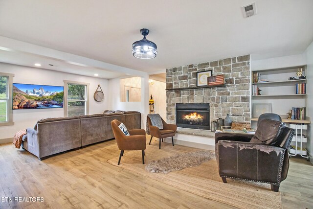 living area with light wood-style floors, visible vents, and a fireplace