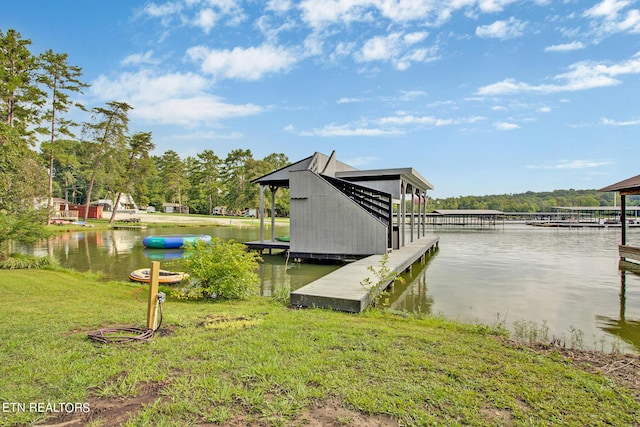 view of dock with a lawn and a water view