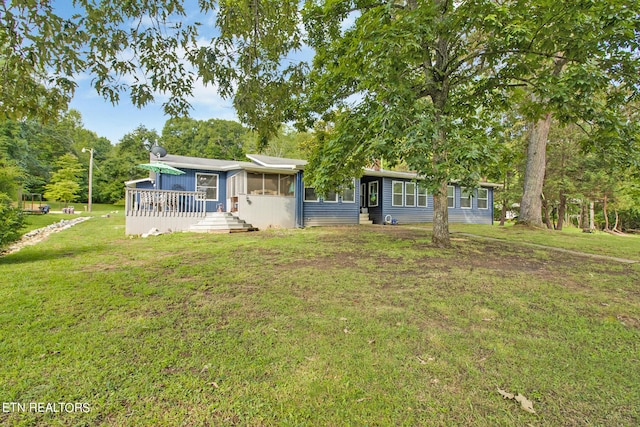 single story home featuring a sunroom, a deck, and a front lawn