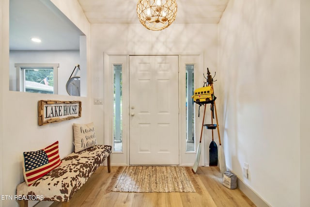 foyer featuring light wood finished floors, baseboards, and a notable chandelier