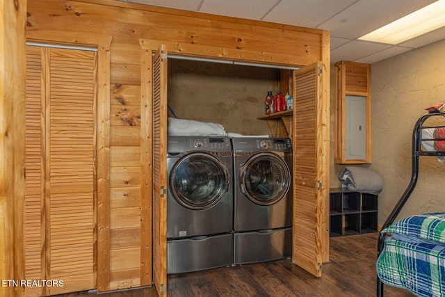 laundry room featuring wood walls, washer and dryer, wood-type flooring, and electric panel