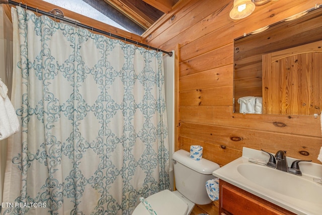 bathroom featuring vanity, wood walls, lofted ceiling, and toilet