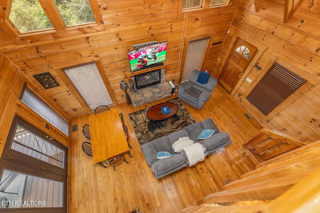 living room with wood walls, hardwood / wood-style flooring, and a towering ceiling