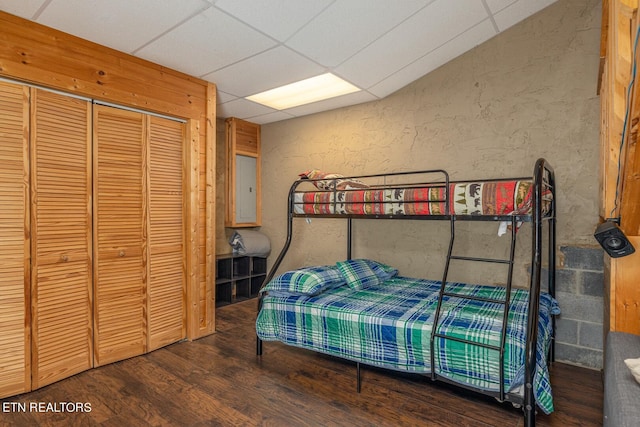 bedroom featuring a drop ceiling, a closet, and hardwood / wood-style flooring