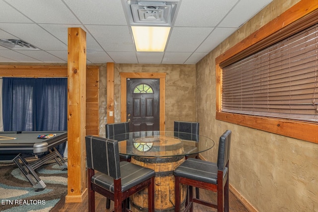 dining room with wood walls, hardwood / wood-style flooring, and a drop ceiling