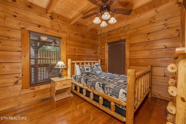 bedroom with ceiling fan, hardwood / wood-style floors, beam ceiling, wood walls, and wood ceiling