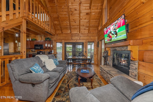 living room featuring a stone fireplace, wood-type flooring, and wooden walls