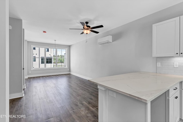 kitchen with light stone counters, a wall mounted AC, backsplash, dark wood-type flooring, and ceiling fan