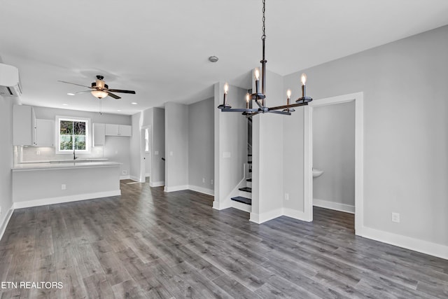 unfurnished living room featuring ceiling fan with notable chandelier, wood-type flooring, a wall unit AC, and sink