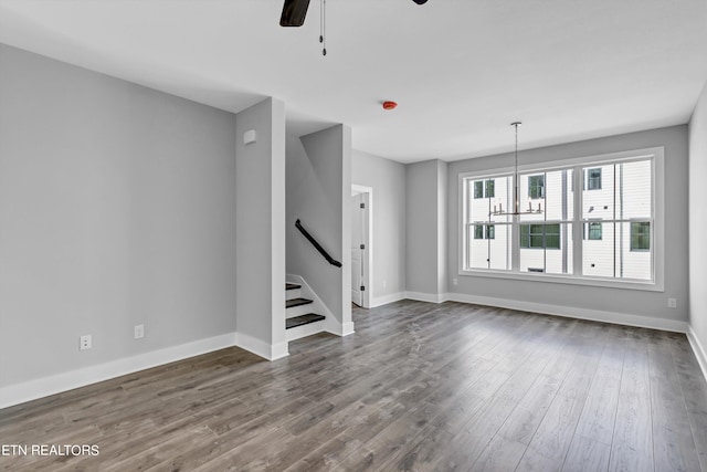 unfurnished living room with ceiling fan with notable chandelier and hardwood / wood-style flooring