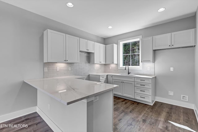 kitchen featuring sink, dark hardwood / wood-style flooring, white cabinets, and backsplash