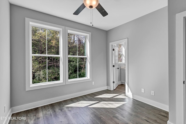 empty room with ceiling fan, dark hardwood / wood-style flooring, and a wealth of natural light