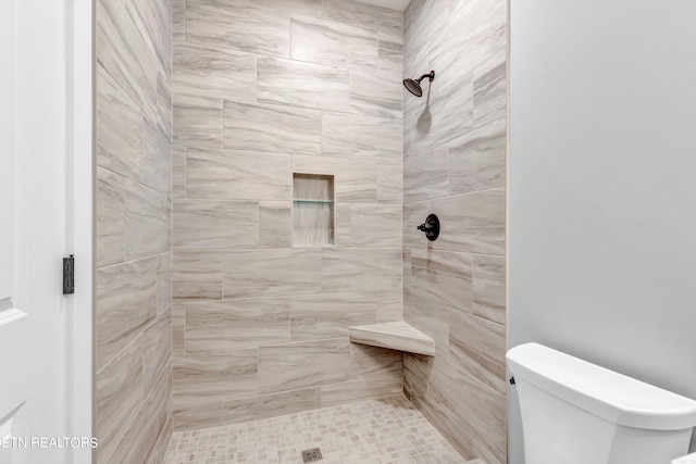 bathroom featuring tiled shower and toilet