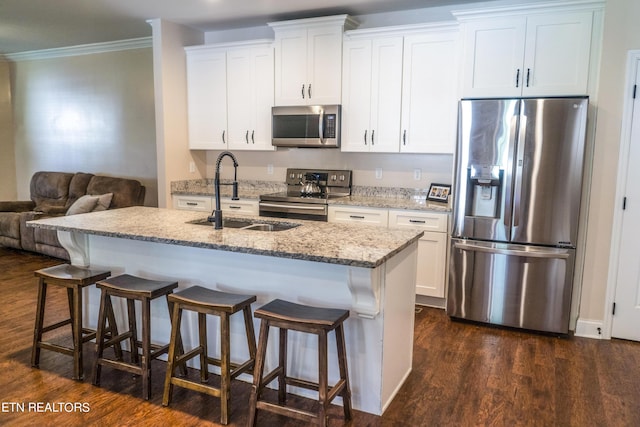 kitchen featuring white cabinetry, sink, stainless steel appliances, and an island with sink