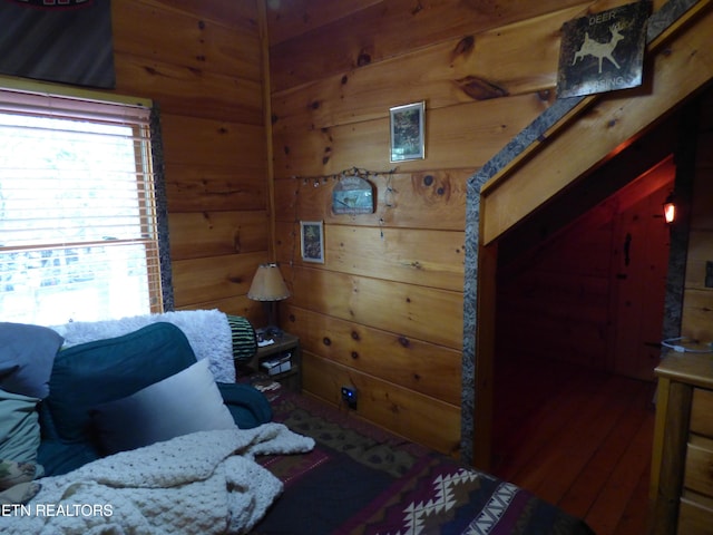 bedroom with hardwood / wood-style floors and wooden walls