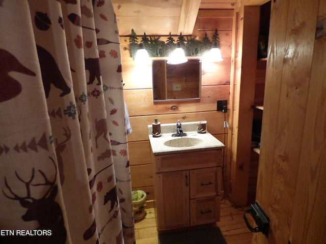 bathroom featuring vanity, hardwood / wood-style floors, and wooden walls