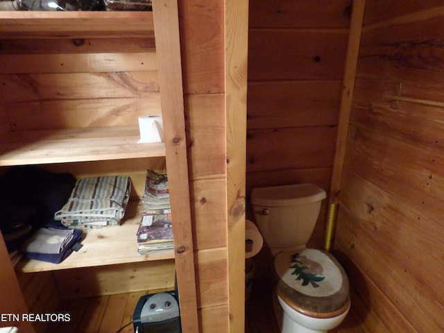 bathroom featuring toilet and wood walls