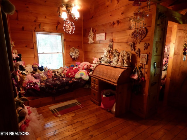 bedroom featuring hardwood / wood-style flooring, a chandelier, and wood walls