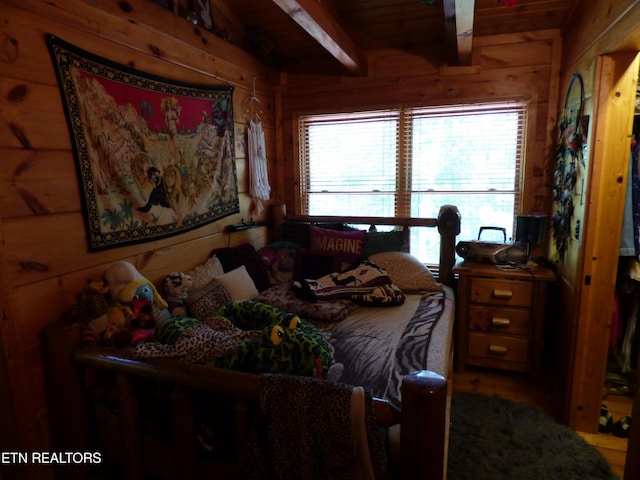 bedroom featuring wooden walls and beam ceiling