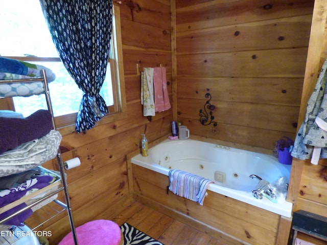 bathroom featuring a bath, hardwood / wood-style floors, and wood walls