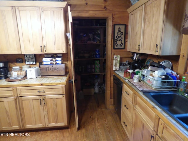 kitchen featuring light brown cabinetry, sink, tile countertops, and black dishwasher