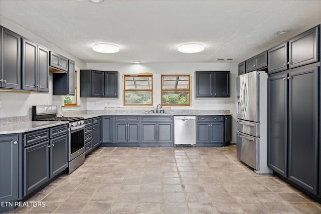 kitchen featuring appliances with stainless steel finishes, sink, gray cabinetry, and a textured ceiling