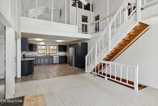 interior space with ceiling fan, sink, hardwood / wood-style floors, and high vaulted ceiling