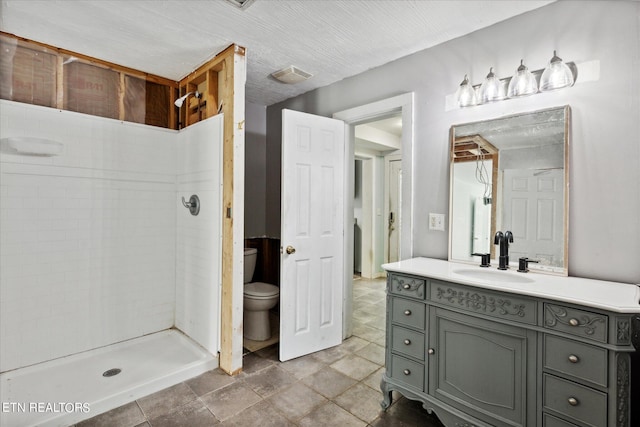 bathroom featuring vanity, toilet, and a tile shower