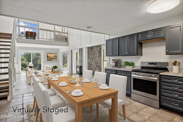 kitchen featuring a high ceiling, gas stove, gray cabinetry, and a textured ceiling