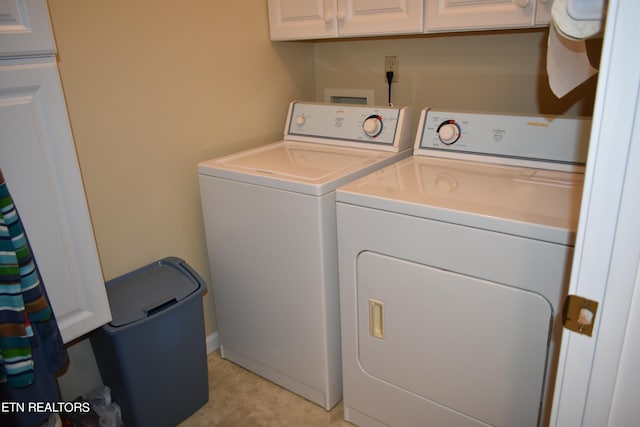 clothes washing area featuring cabinets, washing machine and dryer, and light tile patterned floors