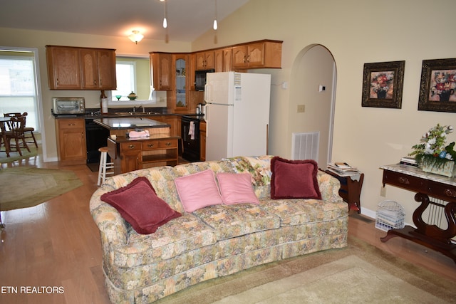 living room featuring light hardwood / wood-style floors, sink, and vaulted ceiling