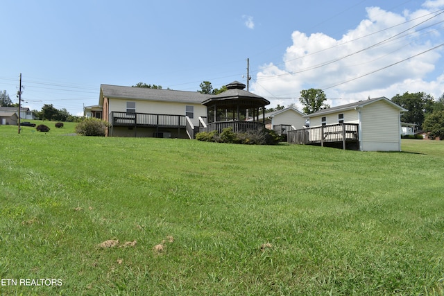 rear view of house with a deck, a gazebo, and a lawn