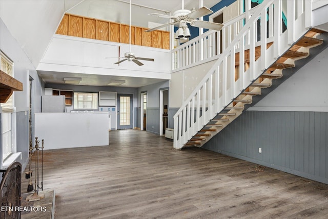 unfurnished living room with a high ceiling, dark wood-type flooring, and ceiling fan